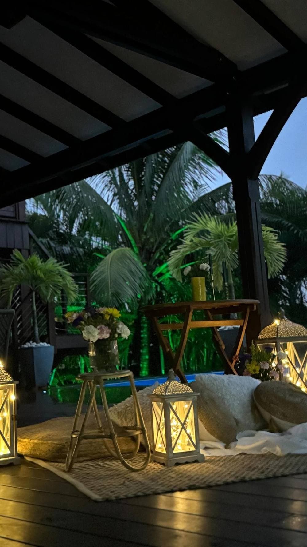 Le deck de la villa et la piscine éclairée à la nuit tombée, sous le carbet