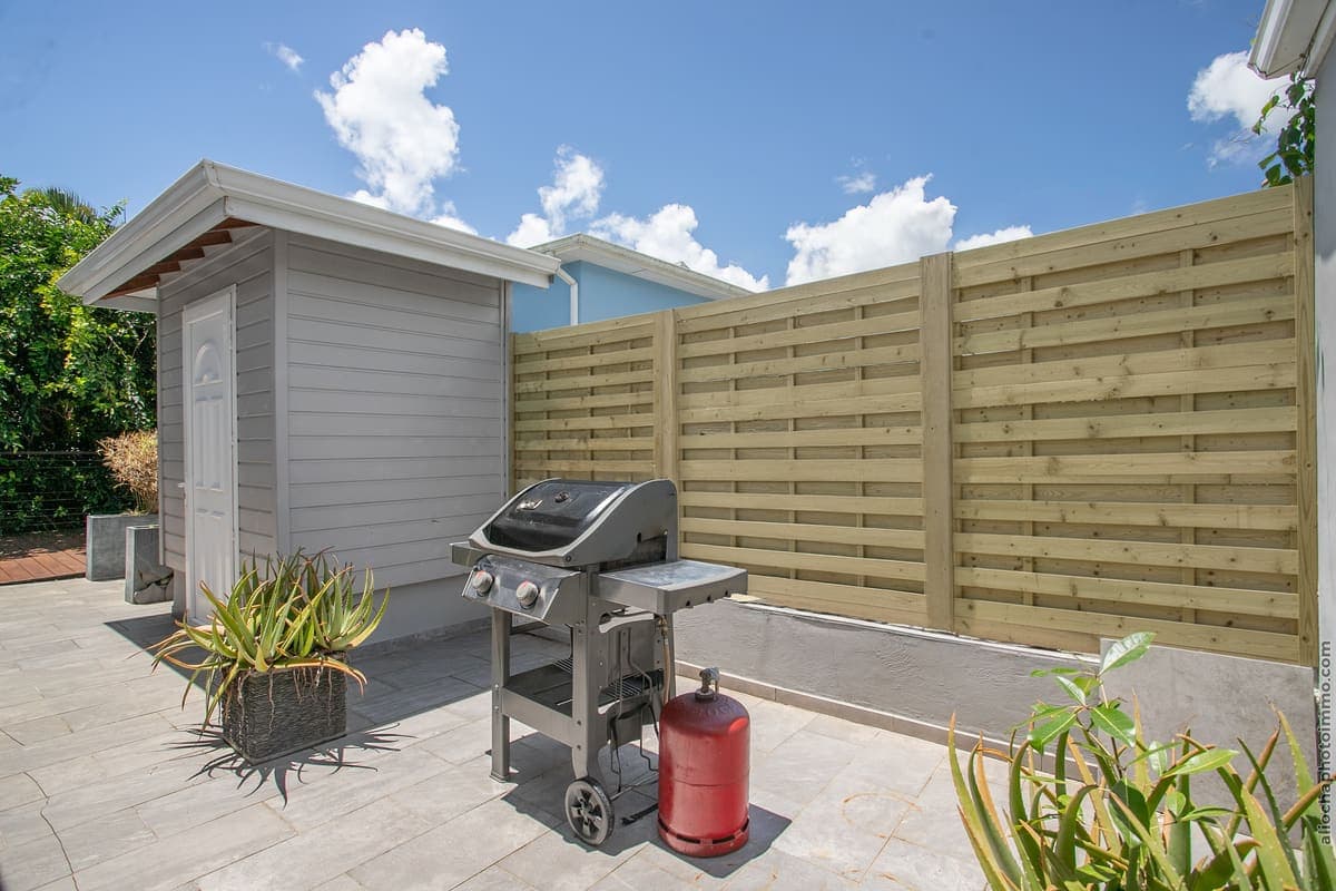 Le barbecue sur sa terrasse, derrière la palissade de bois