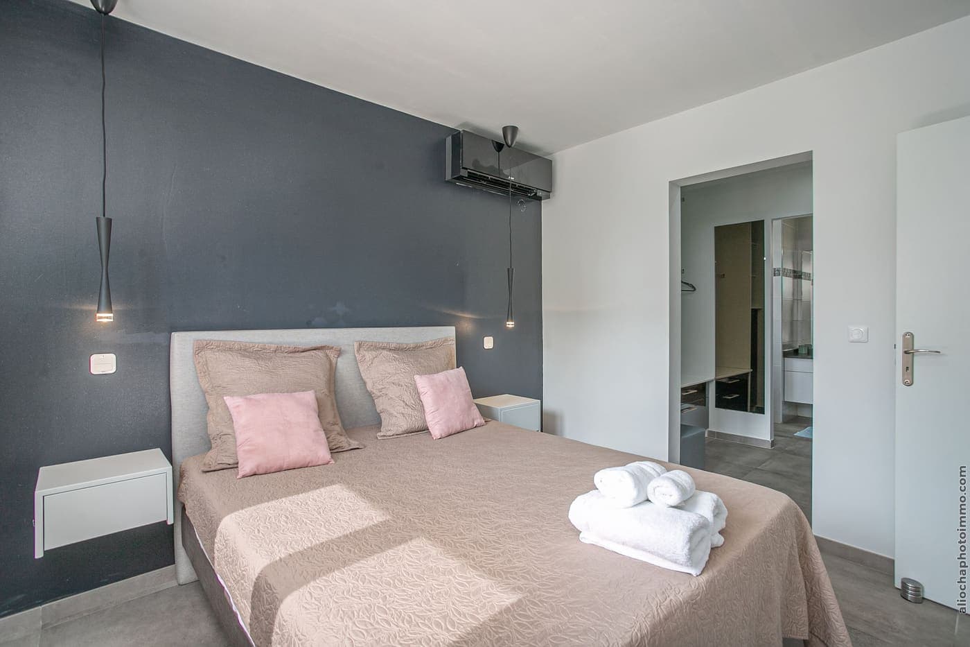 La chambre 1 : lit double, coussins roses, mur d'accent sombre et fenêtre sur le jardin