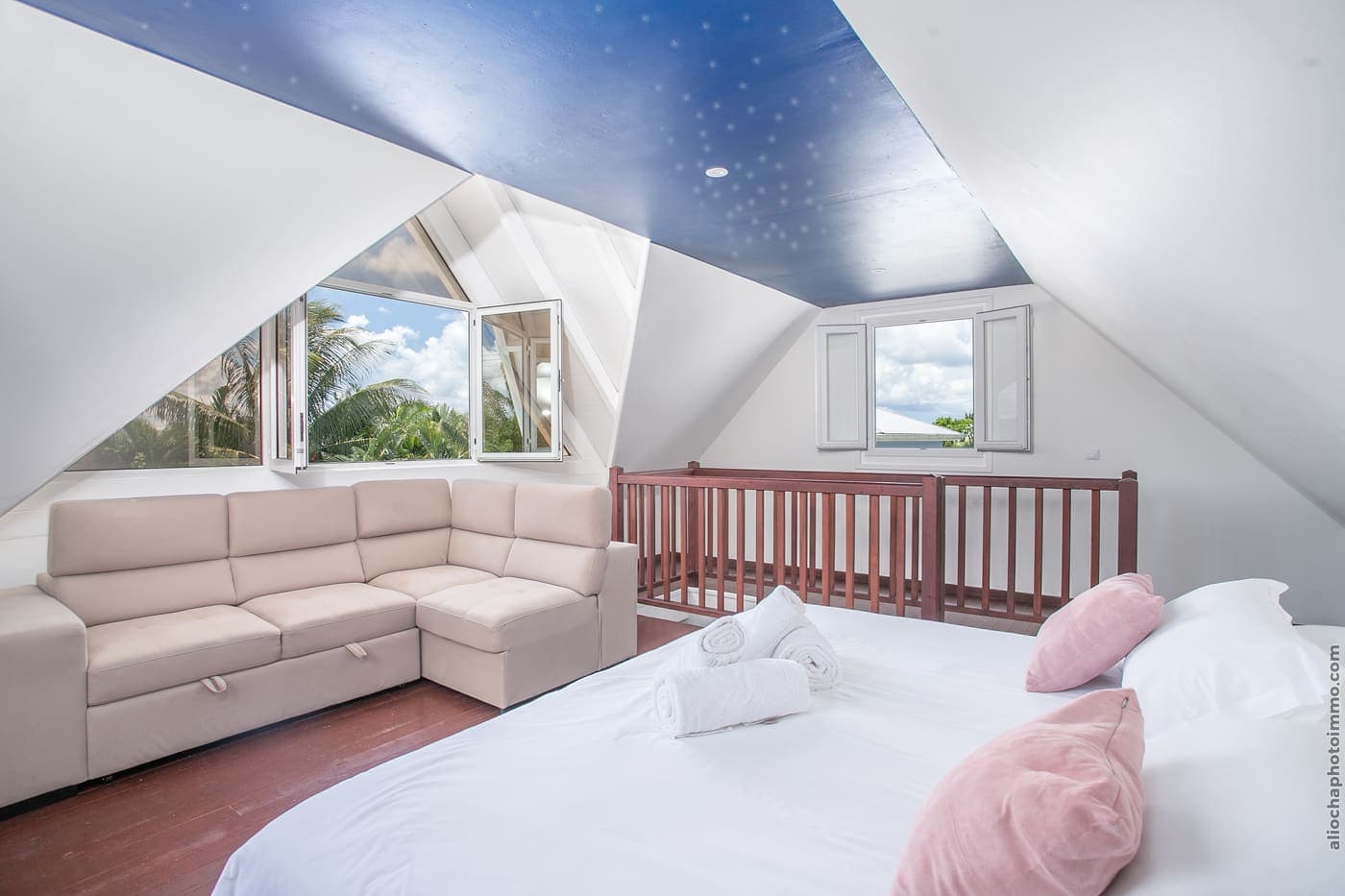La SkyRoom : grand lit, canapé et plafond peint en ciel étoilé, fenêtres ouvertes sur les palmiers